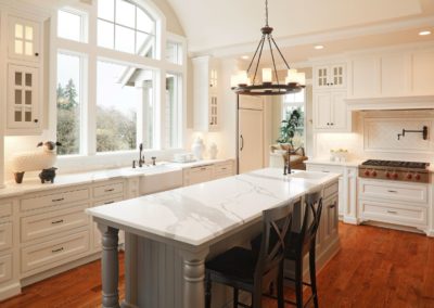 Remodeled kitchen with beautiful hardwood floors, white cabinets and walls, and marble countertops.
