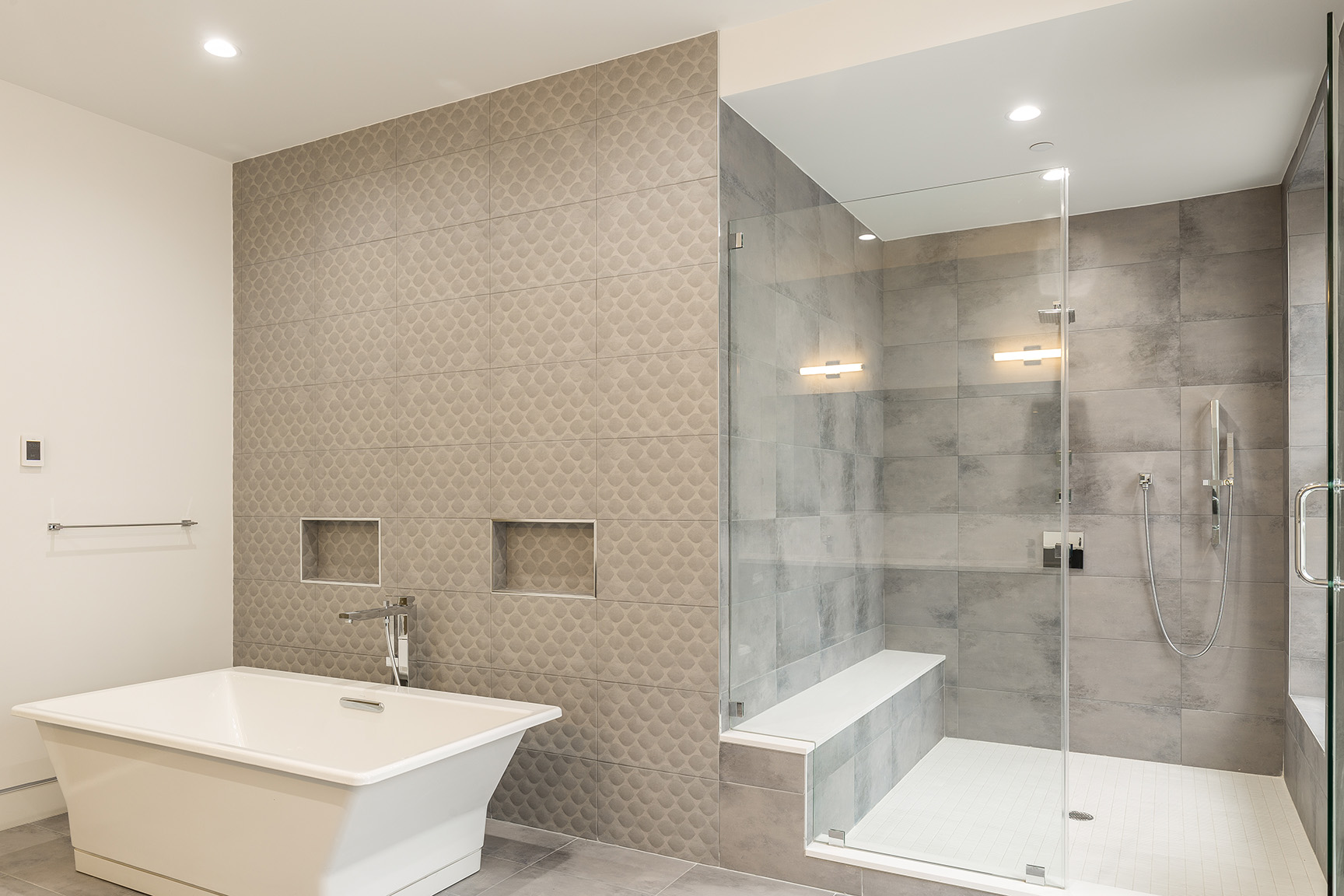 Modern bathroom with textured tiles, freestanding tub, and walk-in shower.