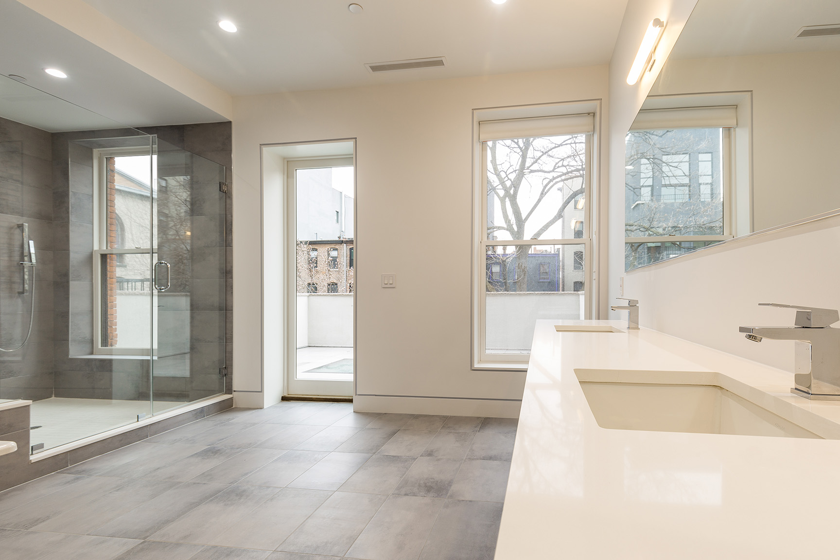 Contemporary bathroom with a glass shower, large windows, and sleek fixtures.