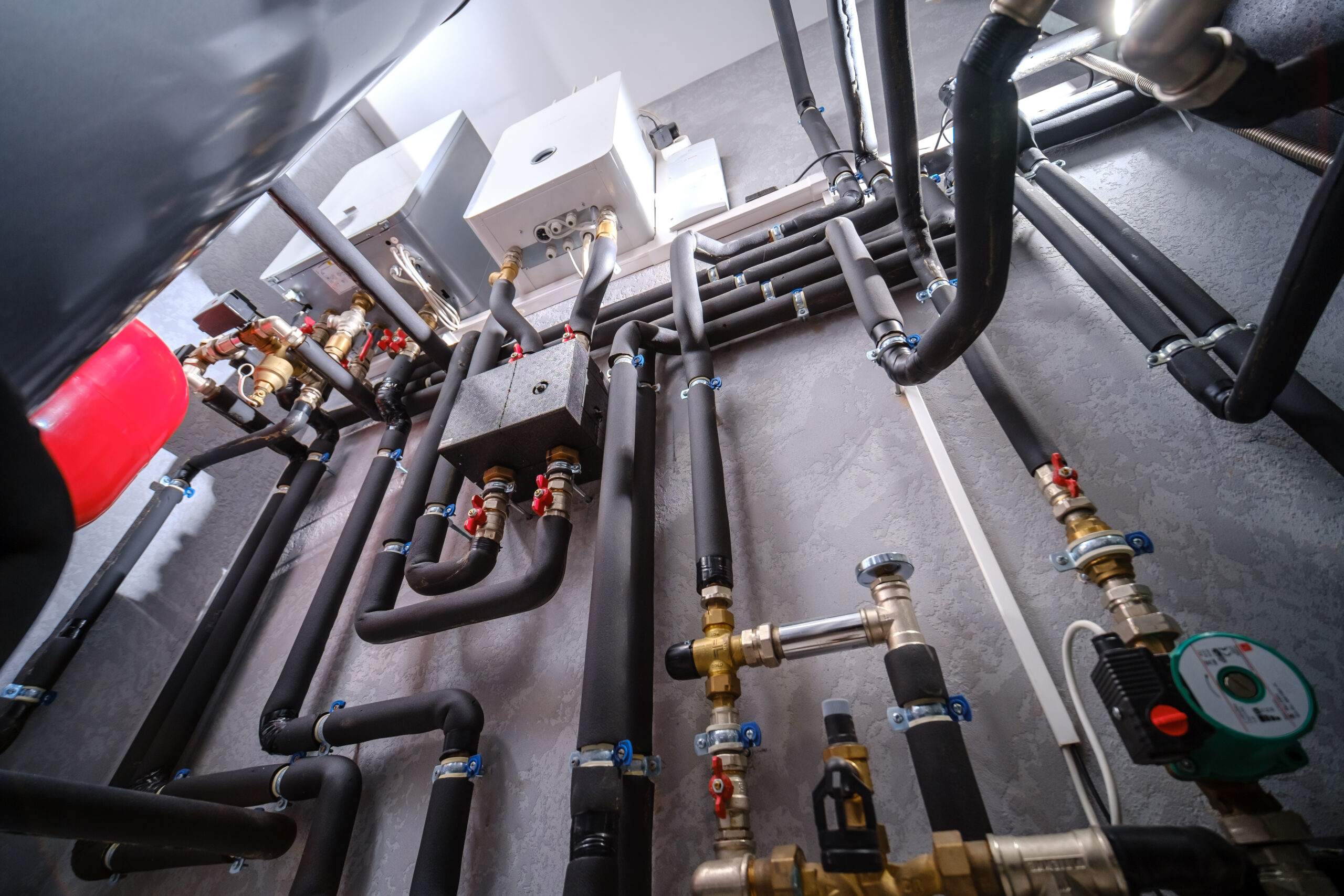 Complex network of pipes and valves in a modern boiler room installation.