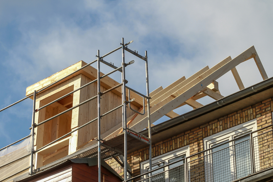 House extension under construction with scaffolding against a blue sky.