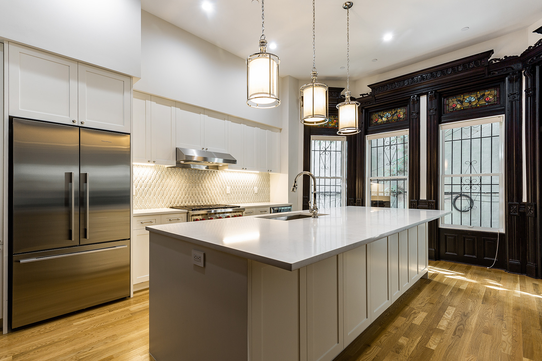 Traditional kitchen with white cabinetry, stainless steel appliances, and hanging lanterns.