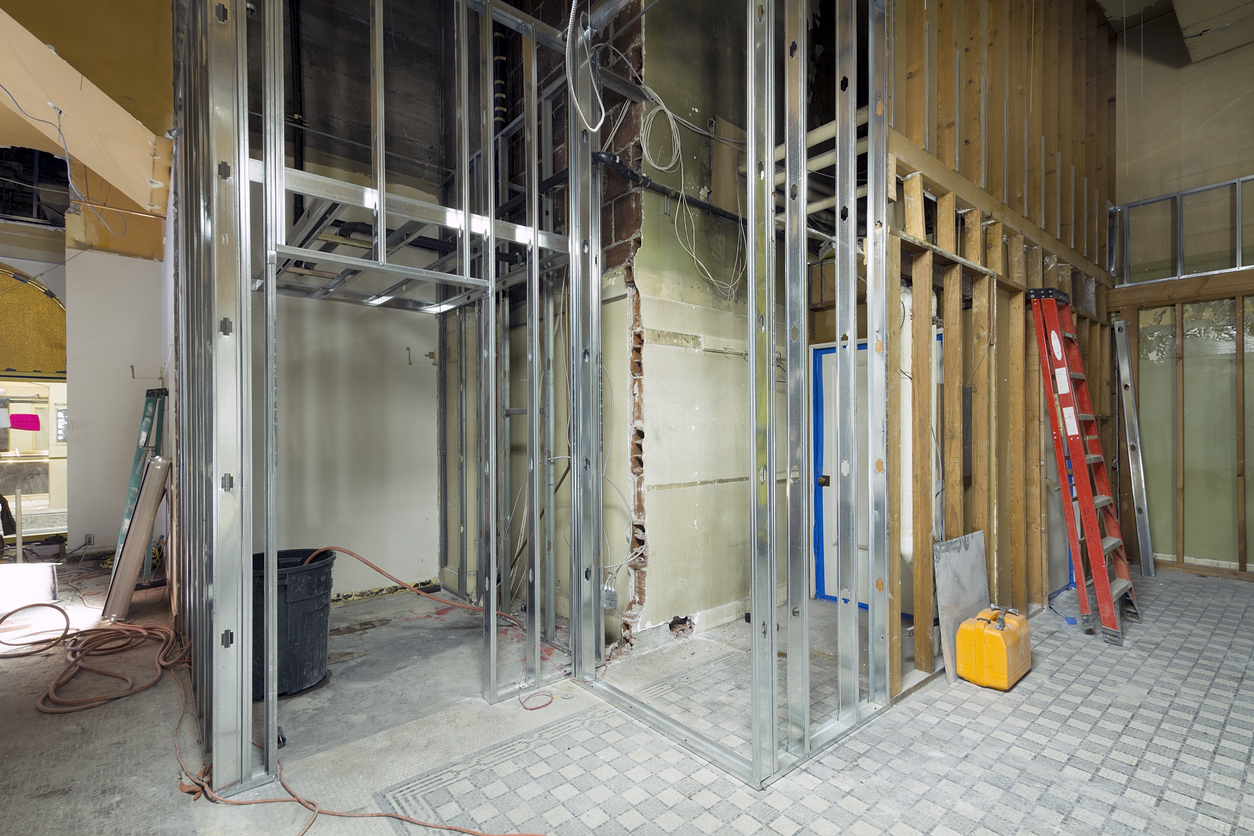 A construction site with metal framing, wiring, and a ladder, indicating an interior space under renovation.